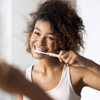 Smiling woman brushing teeth to prevent toothache in Reynoldsburg