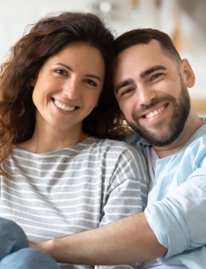 man and woman sitting on couch hugging