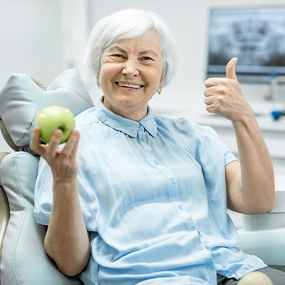 woman holding apple doing thumbs up