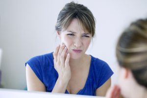 Woman with sore jaw, wondering about bruxism and dental implants