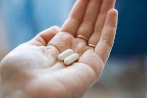 Close-up of a hand holding two ibuprofen pills