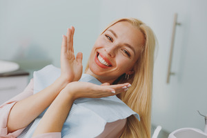 Female patient leaning back in dental chair and smiling